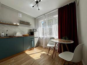 a kitchen with a table and a table and chairs at Квартира - Кэнди in Ustʼ-Kamenogorsk