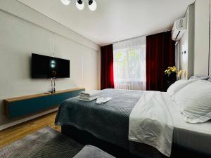 Una habitación de hotel con una cama y un televisor de pantalla plana. en Квартира - Кэнди, en Öskemen