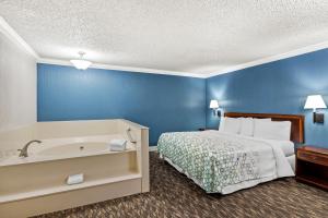 a bedroom with a bed and a bath tub at HomeTowne Studios by Red Roof Yuba City Bonanza - Marysville in Yuba City