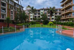 a large blue swimming pool in front of some apartment buildings at Studio flats in Candolim in Candolim