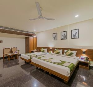 a bedroom with two beds and a ceiling fan at Hotel Vishram Vijayapura Part Of Shubhashree Group in Bijāpur