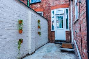 a brick building with a door and potted plants on it at Valla Retreat Serviced Stay in Northampton Town Centre in Northampton