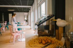 a woman standing in a room with a table and chairs at Hotel Aigue Marine in Tréguier
