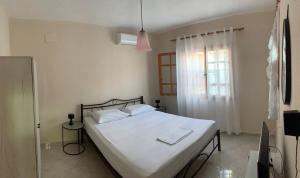 a bedroom with a bed with white sheets and a window at Martha's home in Nea Vrasna