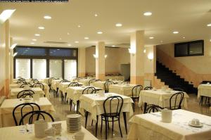 a dining room with white tables and chairs and stairs at Hotel Ideale in Varazze