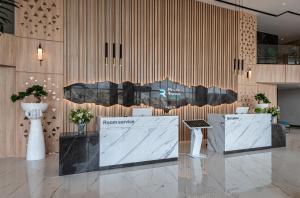 a lobby with two tables and a wall with a sign at Rhenium Hotel Abha in Abha