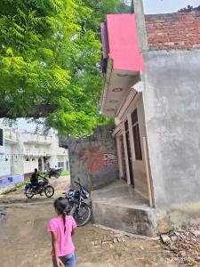 a woman standing outside of a small building at Sundara Home Stay in Lucknow