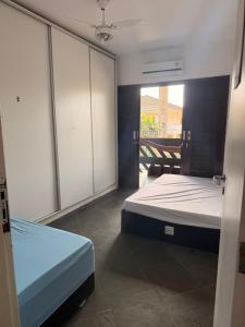 a bedroom with two beds and sliding glass doors at Casa na praia de Bertioga com Pscina e Churrasqueira - até 10 Pessoas in Bertioga