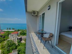 a balcony with a bed and a table and chairs at Green House - Apartment with Separate Room and Sea View in Batumi