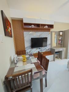Un comedor con mesa y sillas y un televisor. en Rhiangelo Condo Suite in Cebu City, en Cebú