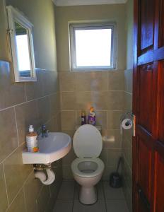 a bathroom with a toilet and a sink and a window at Sunrise On Sea Backpackers in Port St Johns