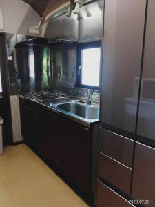 eine Küche mit Spüle und Herd in der Unterkunft ファミーユグループ城ケ崎店 空音sorane in Ito