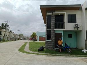 a man sitting on a motorcycle in front of a house at Casa mira coast in Dumaguete Airport