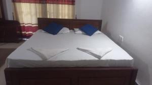 a bed with white sheets and blue pillows at Dream Family Restaurant in Nikawatawana