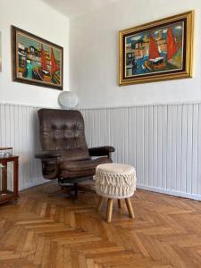 a living room with a leather chair and a stool at Paloznak Retrospektív in Paloznak
