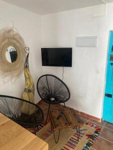 a living room with two chairs and a television on a wall at La Casita Turquesa in Almuñécar