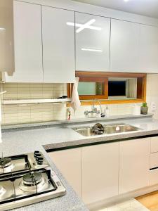 a white kitchen with a stove and a sink at Gangneung Sia Stay in Gangneung