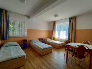 a room with two beds and a table and chairs at Jaśmin -baza noclegowa in Ustka