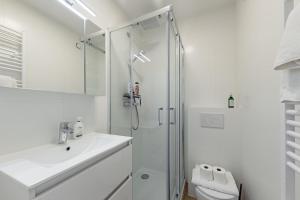 a white bathroom with a shower and a sink at Surreal cocoon in Brussels center in Mellet