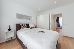 a white bedroom with a large bed and a white cabinet at Surreal cocoon in Brussels center in Mellet