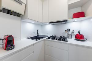 a white kitchen with white cabinets and a red appliance at Surreal cocoon in Brussels center in Mellet +15 photos