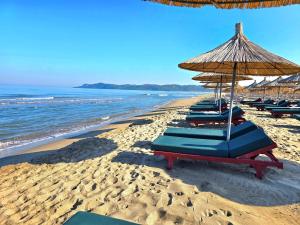 a row of lounge chairs and an umbrella on a beach at Sunny Beach Apartments - 146 in Mullini i Danit