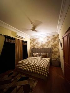 een slaapkamer met een bed met een geruite deken bij Ayyan Cottage F 10 in Islamabad