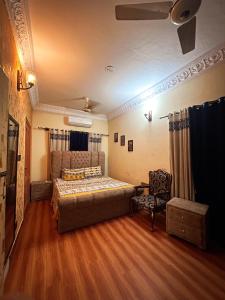 een slaapkamer met een bed en een stoel bij Ayyan Cottage F 10 in Islamabad