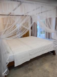 a bed with white mosquito netting in a room at Cozy Cottage in Ahangama