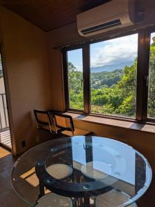 einen Glastisch und Stühle in einem Zimmer mit Fenster in der Unterkunft ファミーユグループ城ケ崎店 海音Umine in Ito