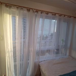 ein Schlafzimmer mit einem Fenster mit weißen Vorhängen in der Unterkunft JFC Inspired Stays PH - Wind Residences Tagaytay in Upli