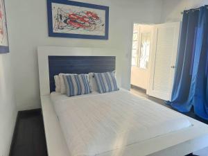 a white bed in a bedroom with blue curtains at Oceanfront Bungalow Cable Beach 2 Bedroom in Macbride