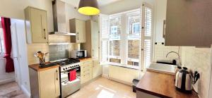 a kitchen with white cabinets and a stove top oven at Double Bed at Cozy Hailsham in London +22 photos