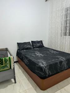 a bed with black sheets in a white room at شقة مفروشة قرب قاعة الحفلآت آحلام in Ksar el Kebir