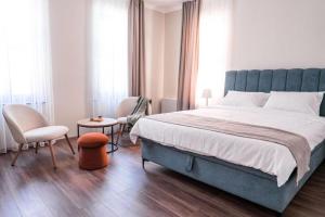 a bedroom with a large bed and two chairs at Harmonia Apartments in Bitola