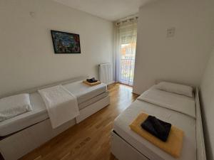 a room with two beds and a window at Niš East gate APT with balcony and free private Parking in Donja Vrežina