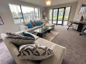 a living room with two couches and a table at Stunning Sea View Home Very near to AKL Airport in Auckland