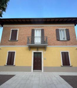 Un edificio amarillo y rojo con un balcón y una puerta. en La Bella Modena Giardini Appartamenti, en Módena 15 fotos más