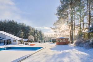 a house with a swimming pool in the snow at Agroturystyka Uroczysko in Sianów