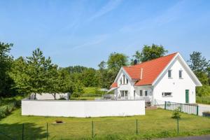 a white house with an orange roof at Poolvilla på Österlen in Brantevik