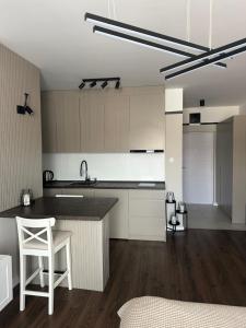 uma cozinha com armários brancos, um balcão e uma mesa em Premium Line Apartman 3 em Sombor mais 2 fotografias