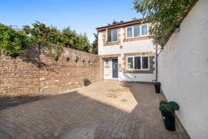 a brick courtyard with a brick wall and a building at Boone - 2 Free Parking,5 minutes walk to Great Southsea Run, 7mins walk to university, Sleeps 1- 7 Comfortably, Driveway, Beach inspired Cozy Garden in Portsmouth