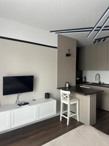 uma cozinha com armários brancos e um balcão com uma televisão em Premium Line Apartman 3 em Sombor
