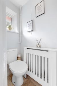 a white bathroom with a toilet and a crib at Boone - 2 Free Parking,5 minutes walk to Great Southsea Run, 7mins walk to university, Sleeps 1- 7 Comfortably, Driveway, Beach inspired Cozy Garden in Portsmouth +11 photos