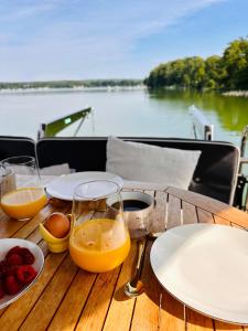 einem Holztisch mit Teller und Gläsern Orangensaft in der Unterkunft TraumZeitBoot Amavida Yacht auf dem Scharmützelsee Bad Saarow in Bad Saarow