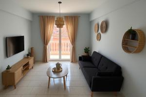 a living room with a black couch and a tv at Ioli's Apartments Zante in Alykes