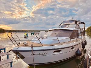 ein Boot liegt an einem Dock im Wasser in der Unterkunft TraumZeitBoot Amavida Yacht auf dem Scharmützelsee Bad Saarow in Bad Saarow
