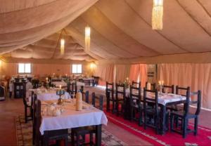 a dining room with tables and chairs in a tent at Host Luxury Camp in Merzouga