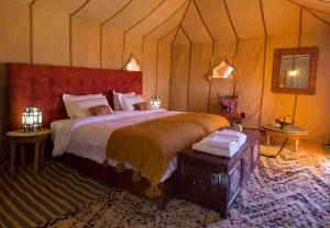 Un dormitorio con una cama grande en una tienda de campaña. en Host Luxury Camp, en Merzouga