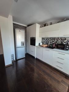 a kitchen with white cabinets and a wooden floor at Апартамент Хан Крум in Yambol +11 photos
